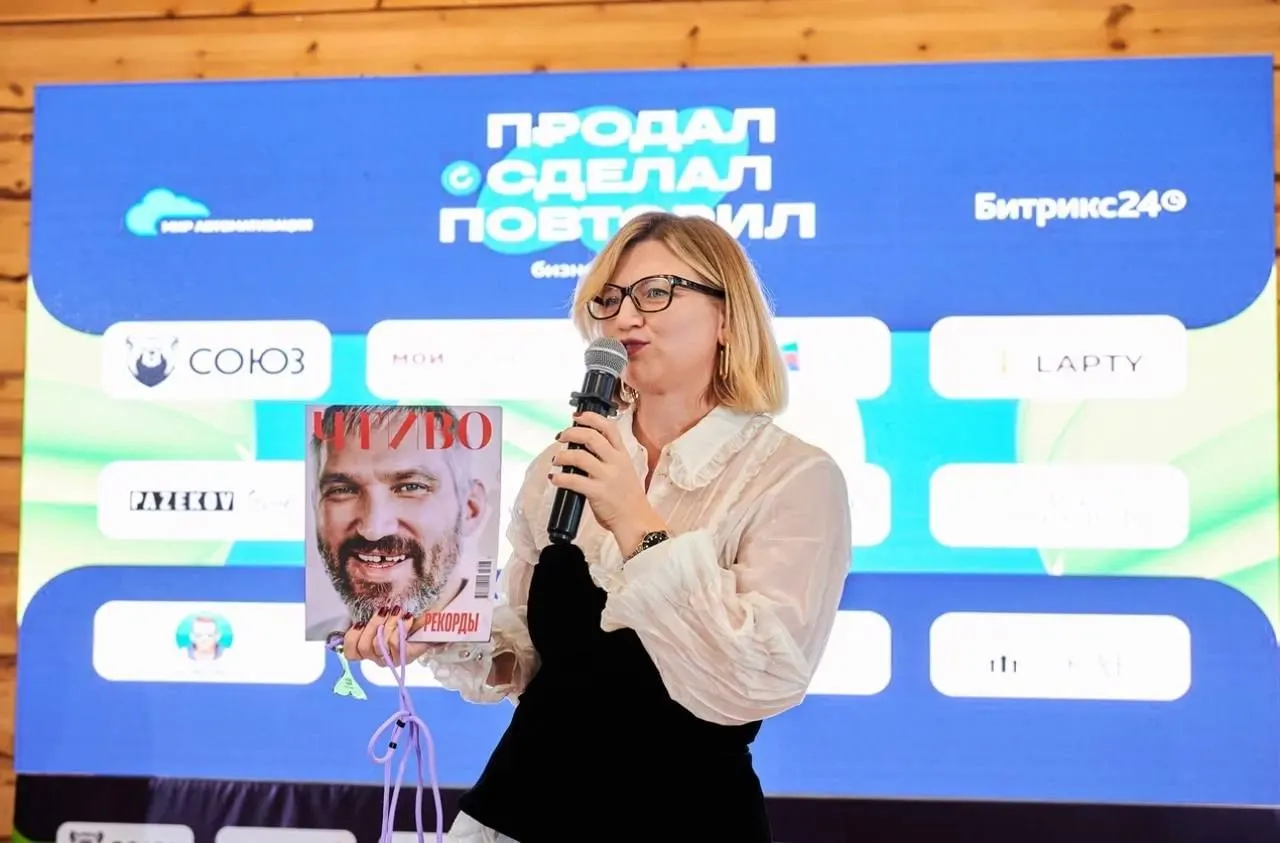 Ирина Сальникова на сцене бизнес-форума у большого экрана